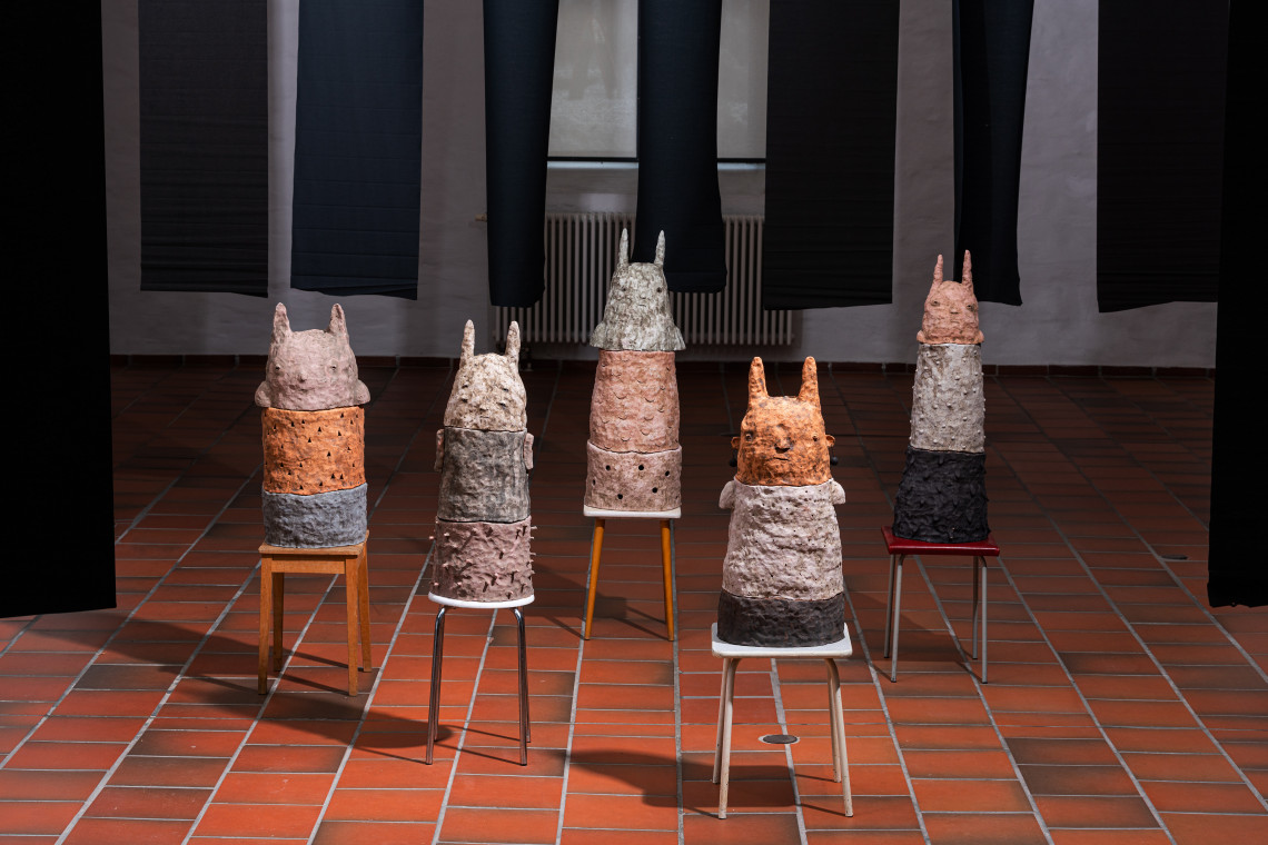 Fünf keramischen Plastiken stehen auf Hockern in Gruppe auf dem Kunsthallen-Fliesenboden. Die Plastiken sind inspiriert vom Volksgut der Wilden Männle sowie den alemannischen Sagen