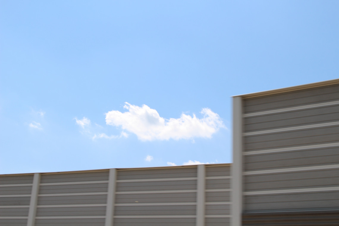 Schallschutzwand, dahinter blauer Himmel mit einer Wolke