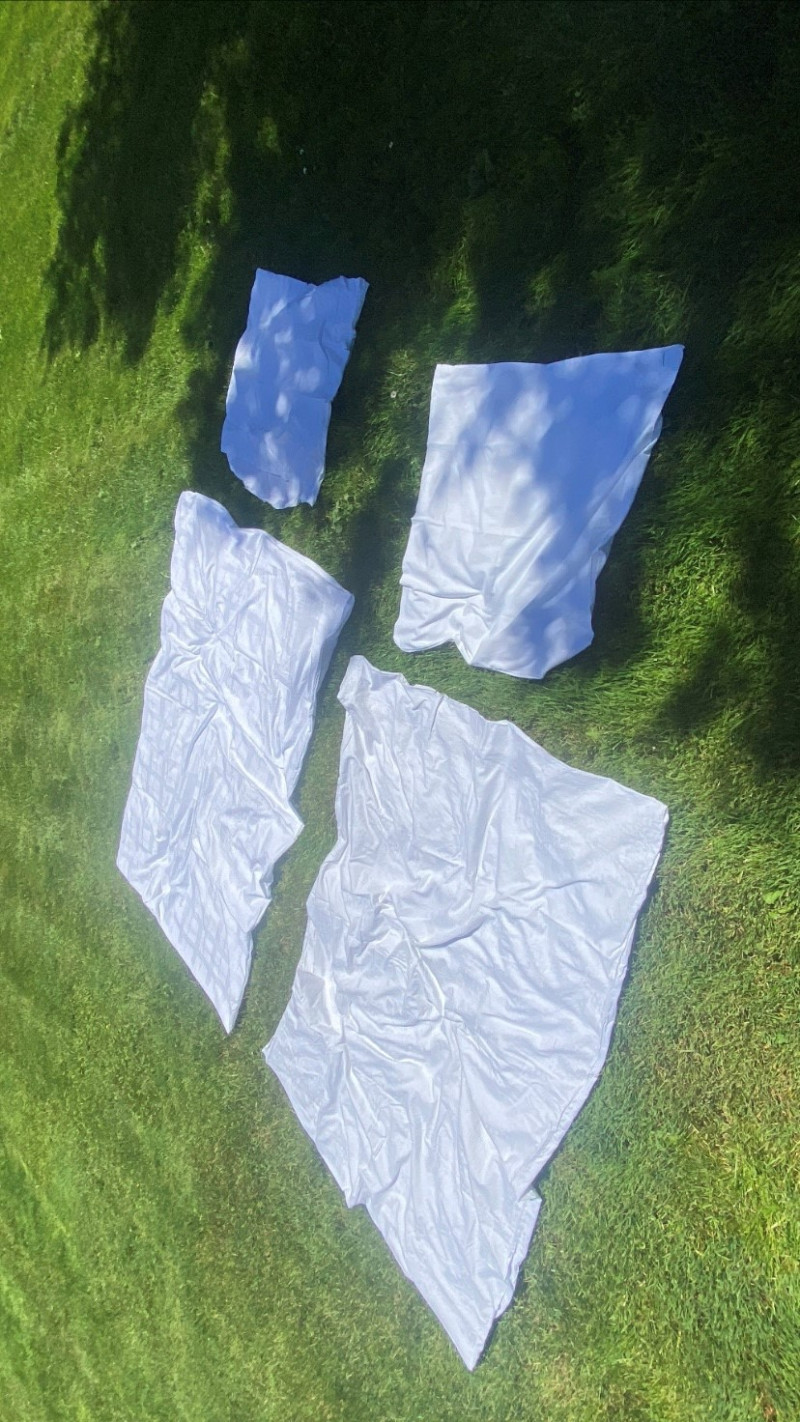 ausgebreitete weiße Bettwäsche auf Wiese liegend