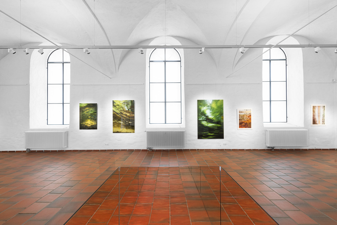 Glaskasten, stehend in der mitte der Kunsthalle, an der Wänden Fotoaufnahmen von Flüssen