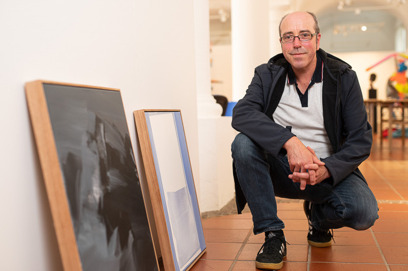 Künstler Stefan Winkler neben zwei Gemälden
