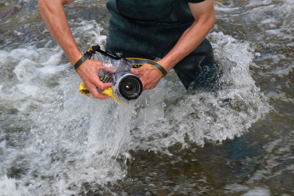 Schilling stehend in Fluss verpackt Kamera in wasserdichten Beutel